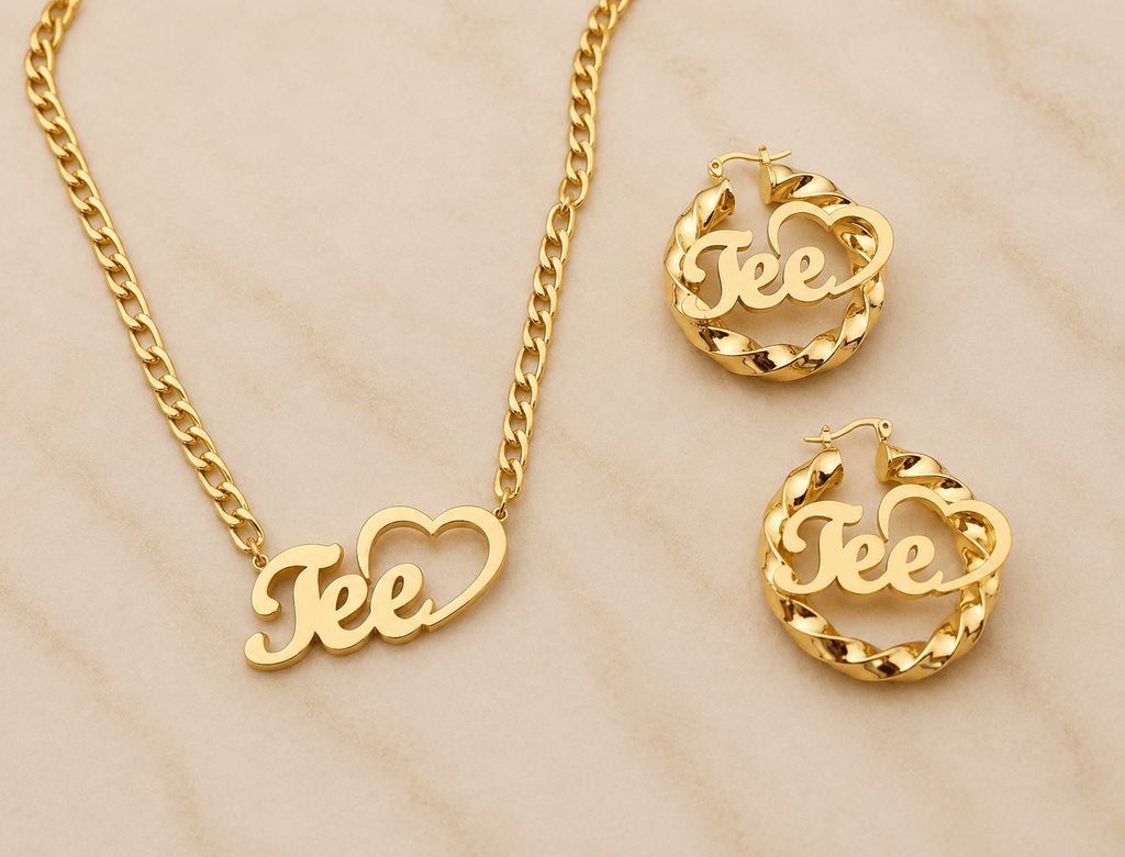 Gold jewelry set featuring a chain necklace and matching hoop earrings, each with a heart-shaped pendant containing the script name 'Tee'.