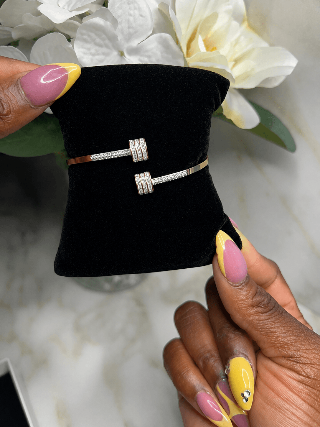 The Imperial Twist Bracelet displayed on a black velvet cushion, showcasing its elegant twisted design with sparkling details.