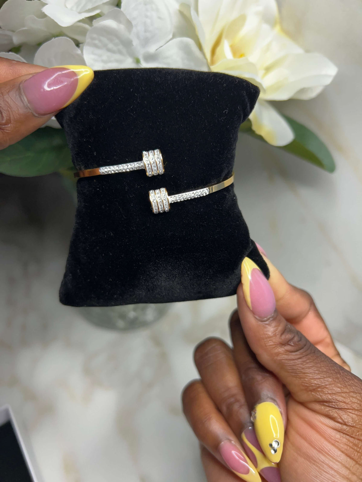 The Imperial Twist Bracelet displayed on a black cushion, showcasing its elegant twisted design and shimmering details.