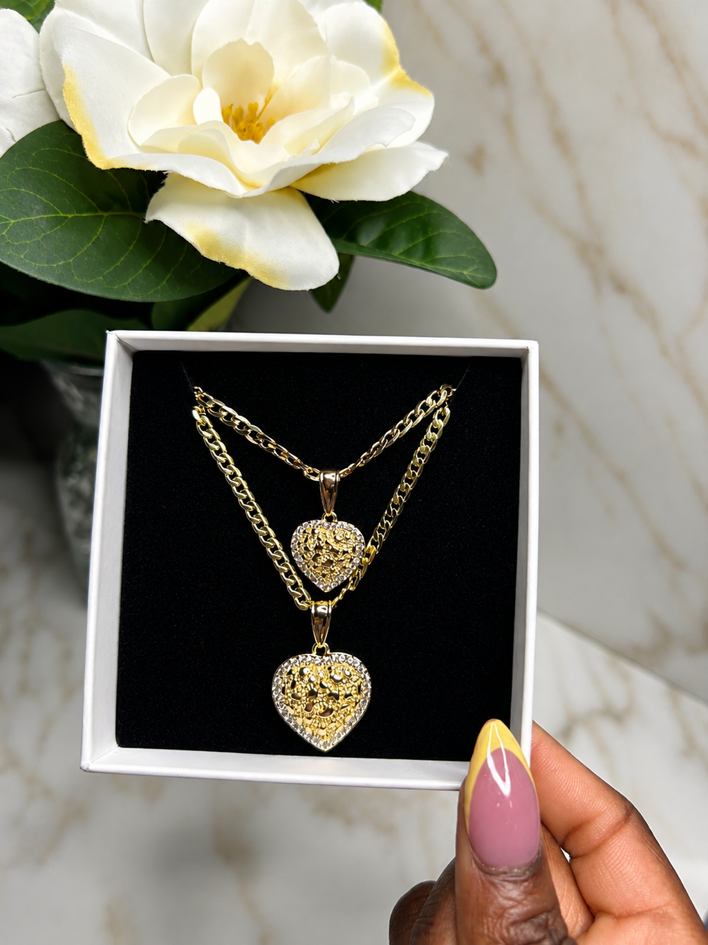 The Royal Heart Bond Necklace displayed in a box, featuring gold chains and heart pendants, symbolizing mother-daughter love.